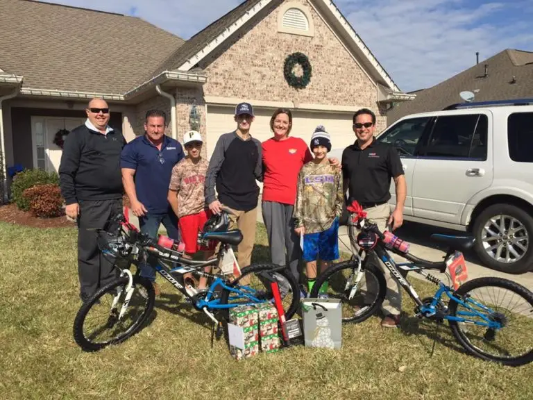 APS personnel posing with a family receiving donated bicycles and Christmas presents