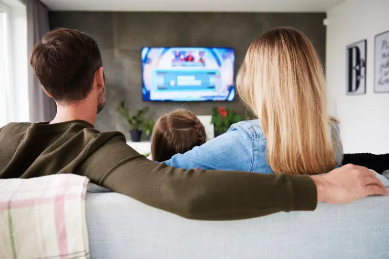 Family sitting on a couch watching TV, showcasing integrated entertainment systems