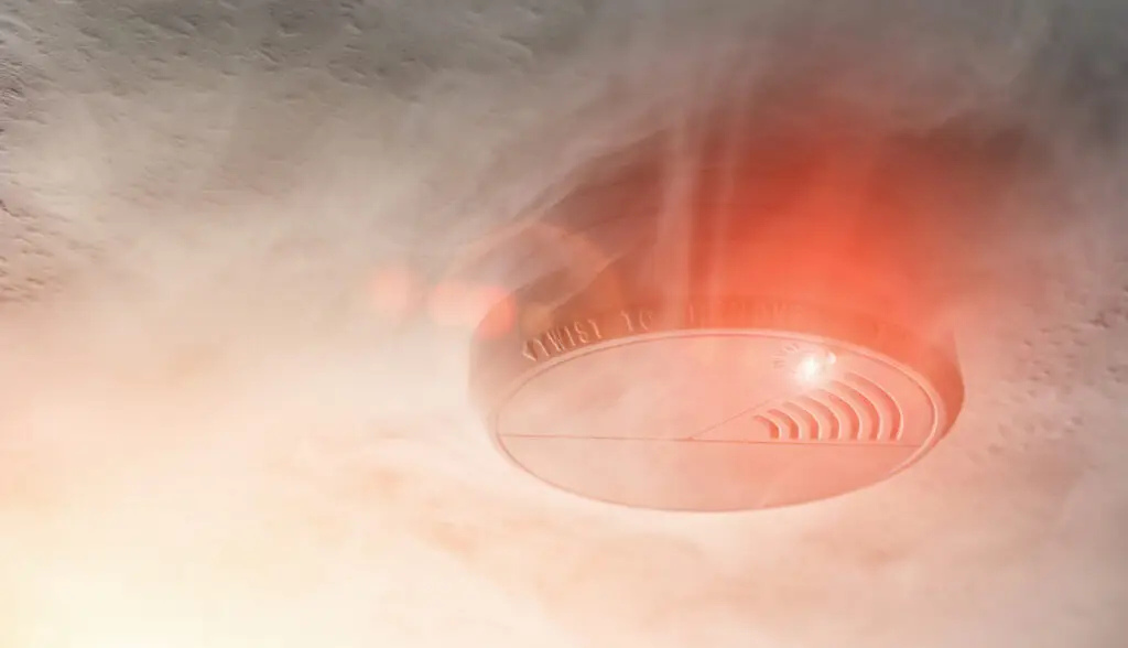 Home smoke detector for fire protection with a red light surrounded by smoke