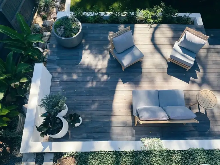 Aerial view of a deck with wooden furniture, cushions, and planters for outdoor entertainment